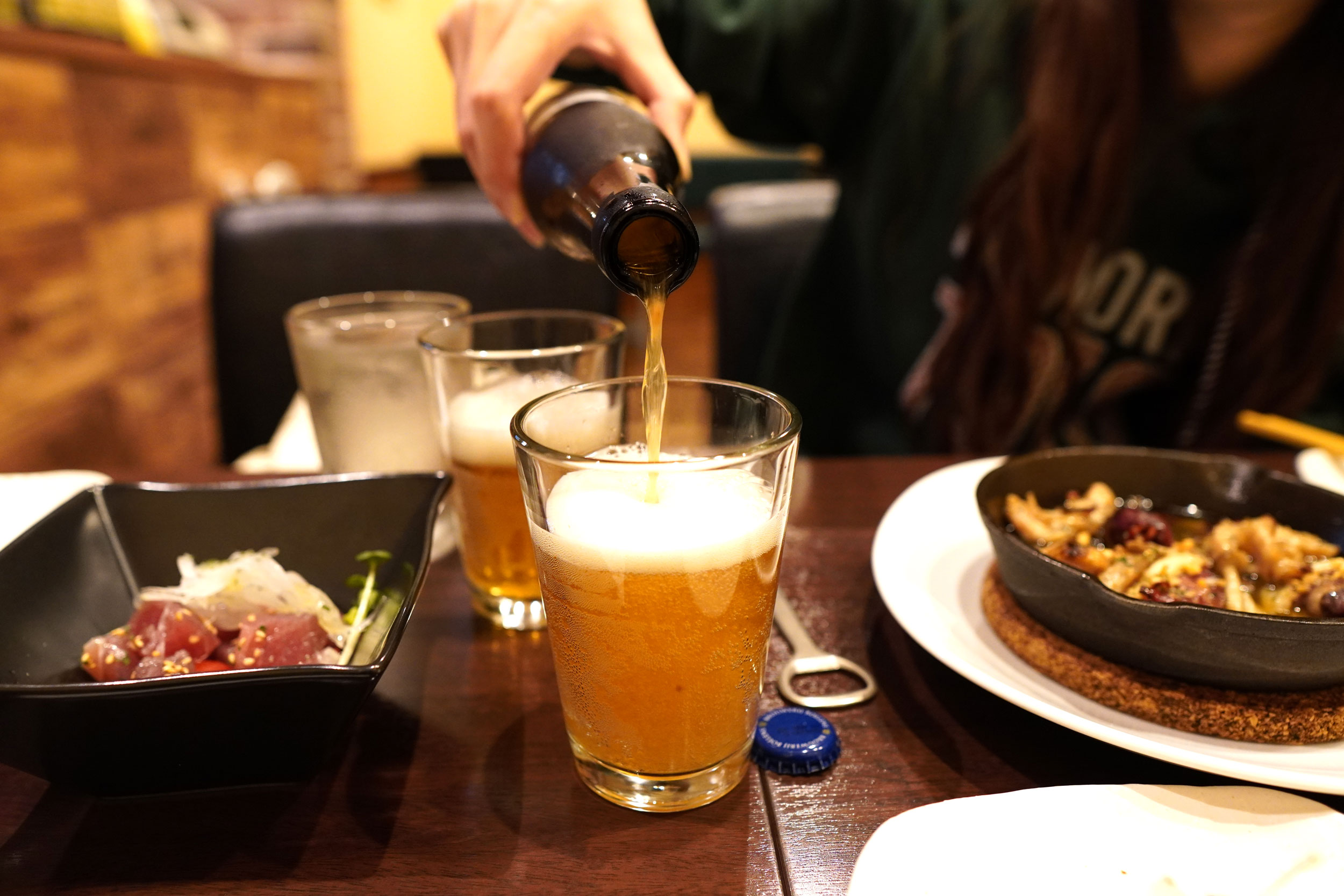 海外のクラフトビール、Bieken（ビーケン）をグラスに注いでいる女性の写真。